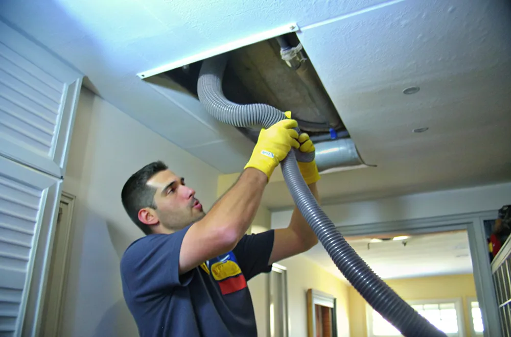 residential-cleaning a HVAC cleaner putting a pipe into a unit to clean it