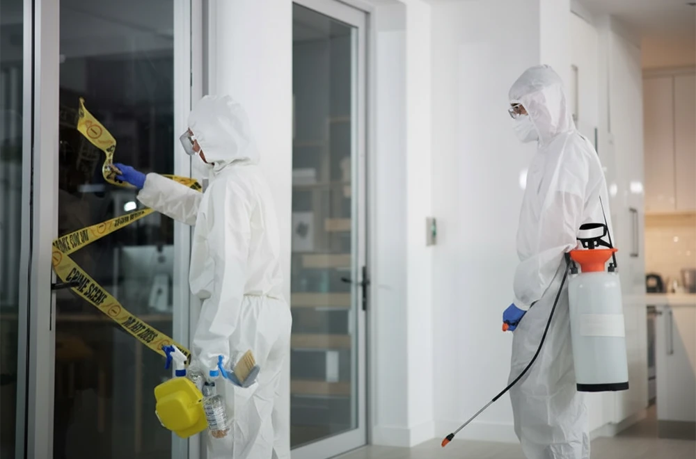 two people wearing hazmat suits entering a crime/trauma scene