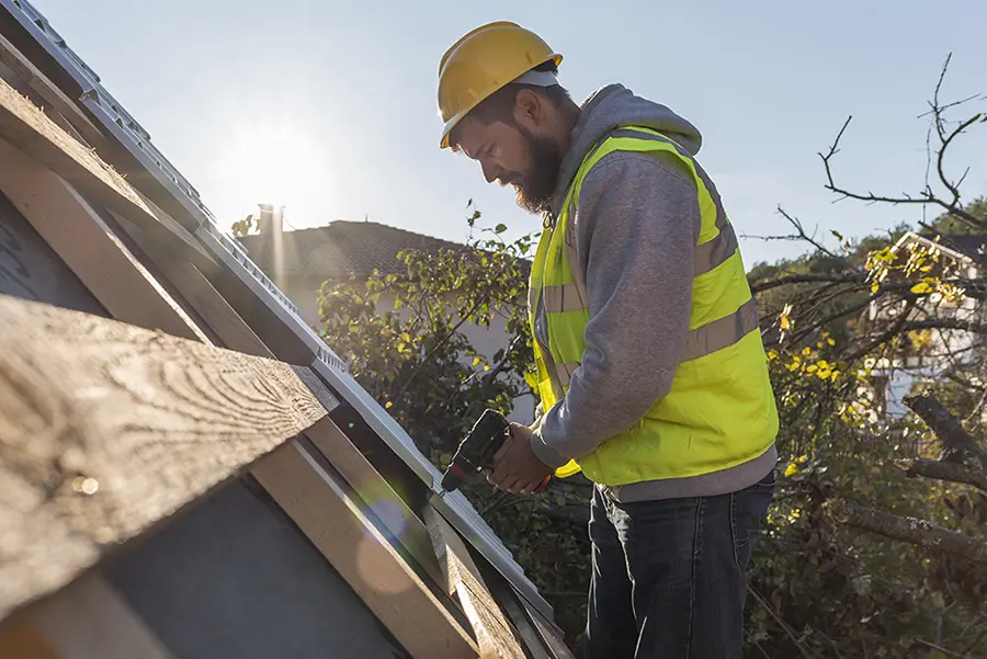a worker fixing a house roof after a storm
