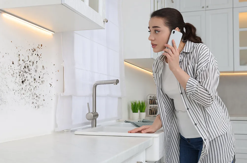 mold-in-a-house woman looking at mold on her kitchen wall