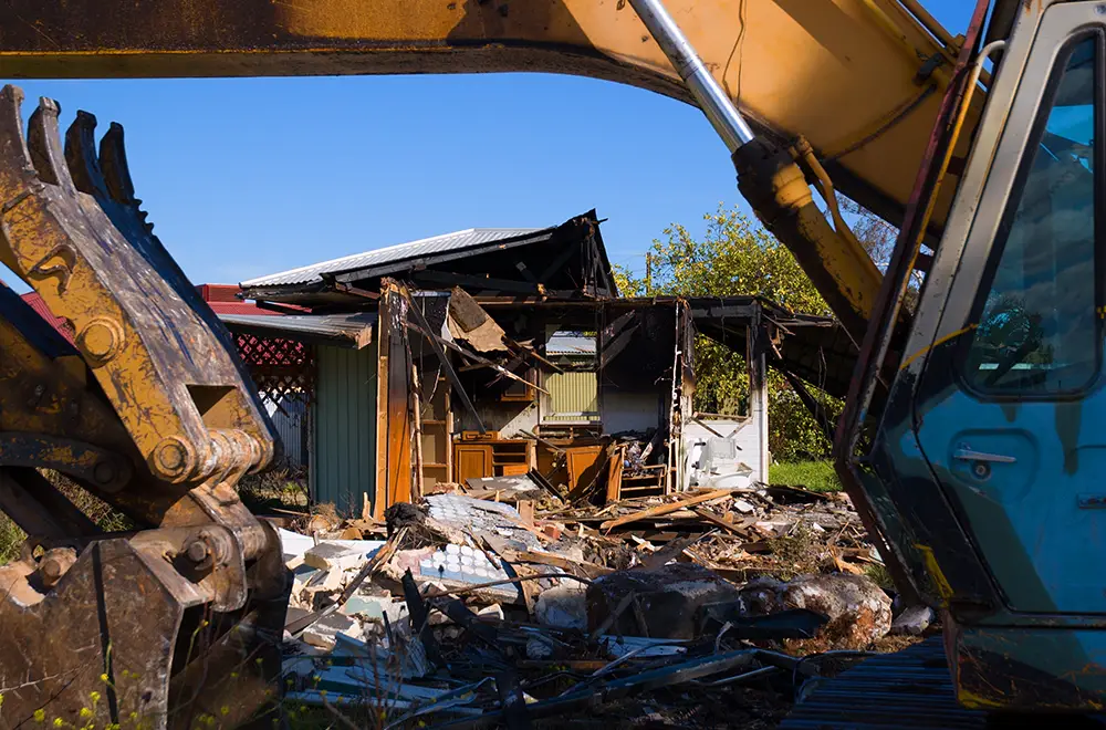 a crane removing debris from a broken house